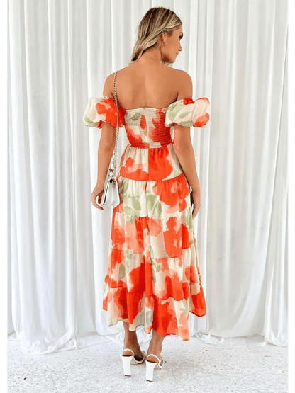 Back view of a woman wearing the Sunset Bloom Maxi Dress with off-shoulder sleeves and tiered ruffles in floral design.