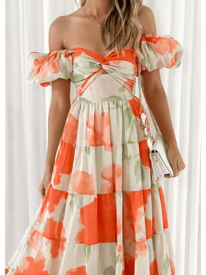 Model wearing the Sunset Bloom Maxi Dress, an off-shoulder design with tiered ruffles and vibrant floral print.