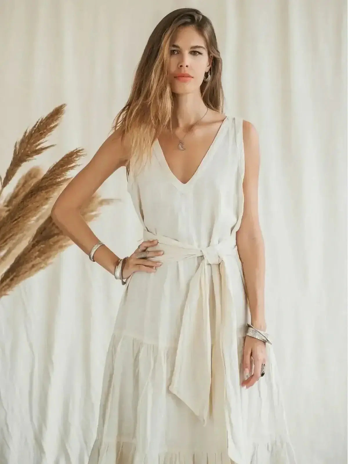 Woman in a light beige Suntrace Maxi Dress featuring a deep V-neckline and wide belted waist, exuding effortless summer style.