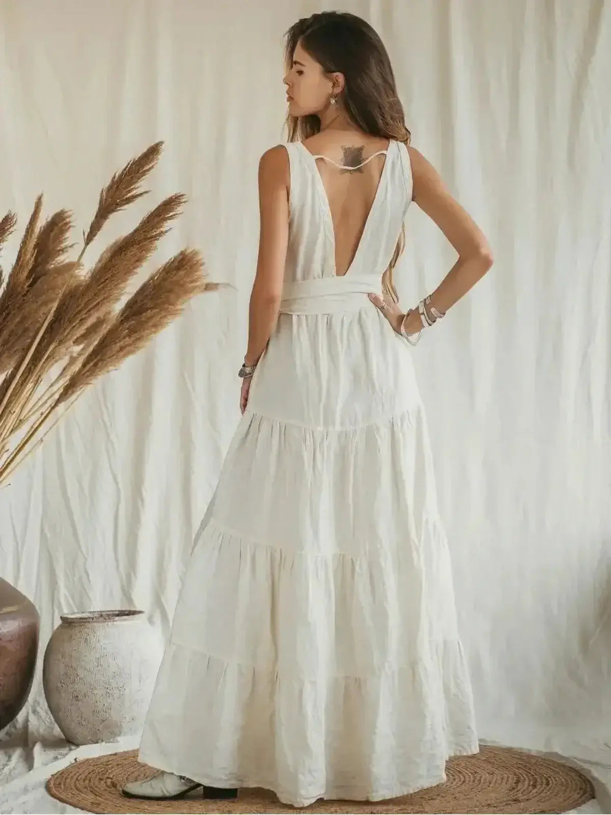 Suntrace Maxi Dress in lightweight beige linen with deep V-back and tiered hem, styled against a neutral backdrop.