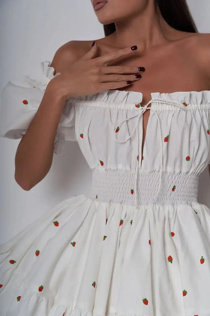 Thea Mini Dress featuring puff sleeves, a milkmaid neckline, and a smocked waist, adorned with strawberry patterns.