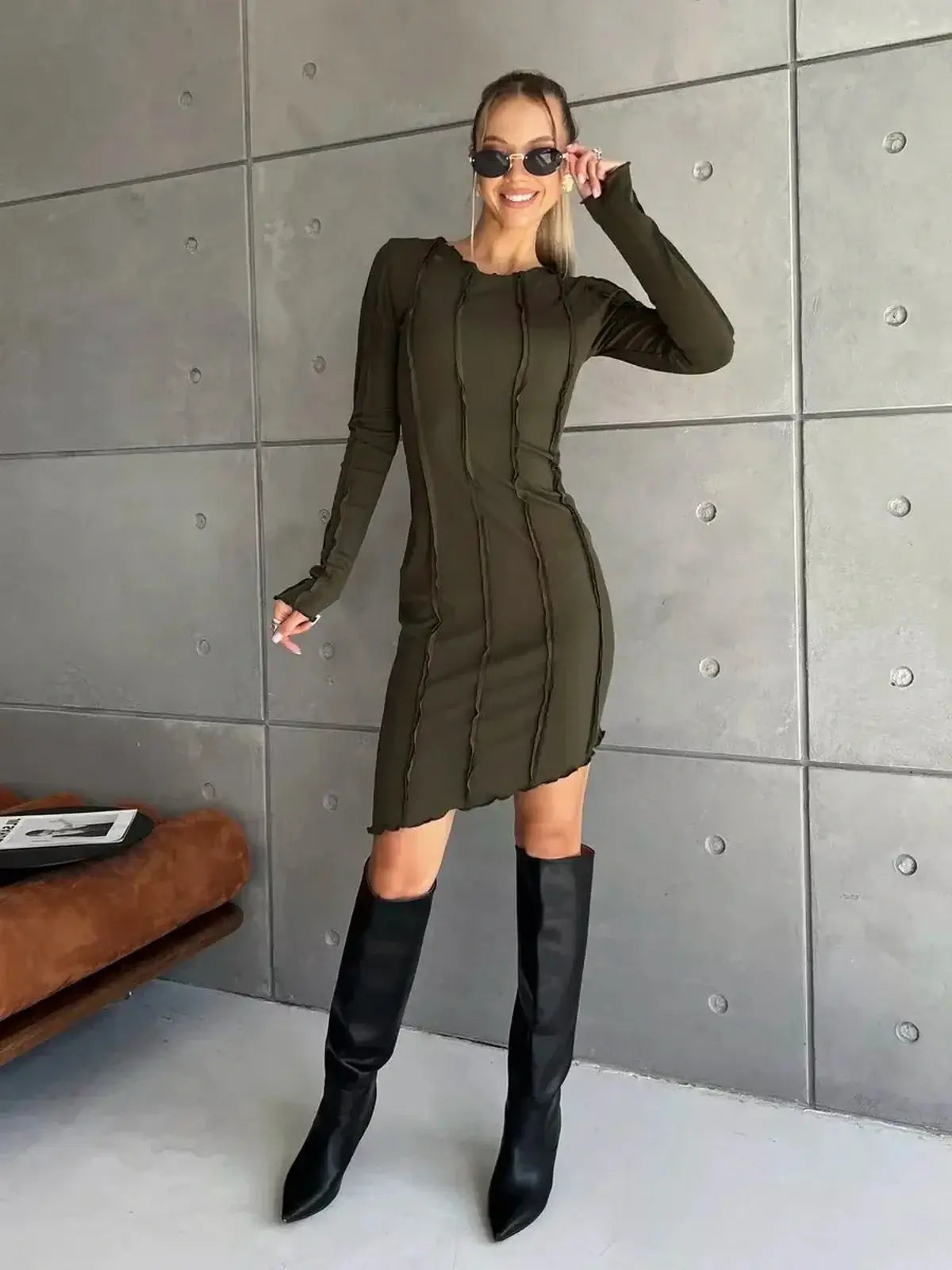Model showcasing an olive green Urban Edge mini dress with long sleeves and contrast-stitch detailing.