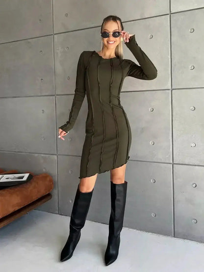 Model showcasing an olive green Urban Edge mini dress with long sleeves and contrast-stitch detailing.