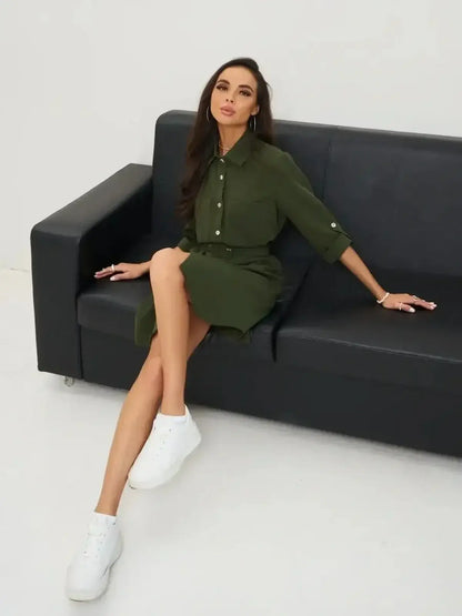 Urban Utility belt mini dress in olive green, styled with white sneakers, perfect for warm weather and city evenings by Lauven.