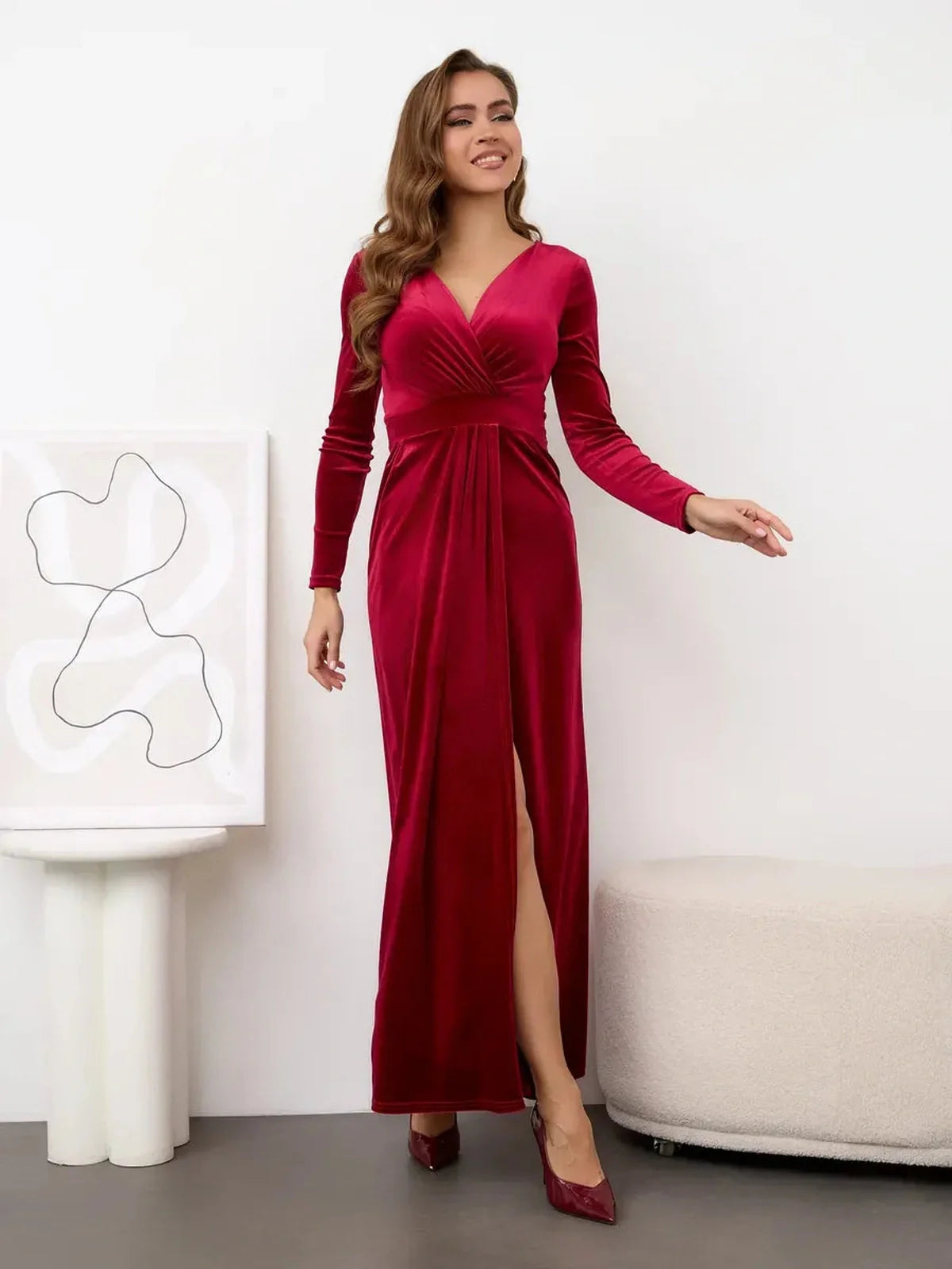 Elegant woman in a wine red Velvet Allure Maxi Dress featuring a thigh-high slit and soft draping for a luxe look.