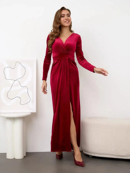 Elegant woman in a wine red Velvet Allure Maxi Dress featuring a thigh-high slit and soft draping for a luxe look.