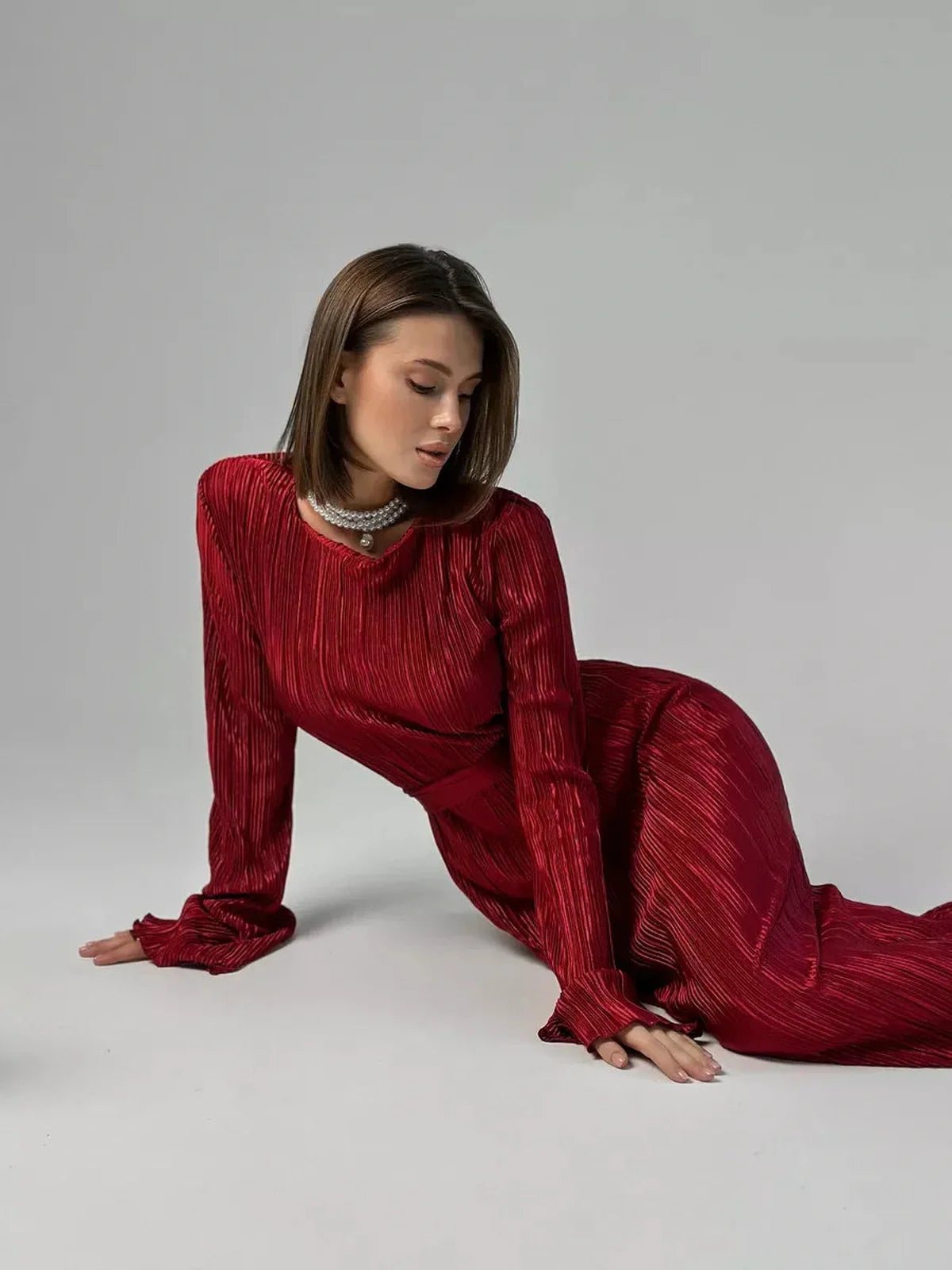 Model showcasing Velvet Flame Maxi Dress in glossy marsala red with pleats and flared sleeves, styled elegantly for formal occasions.