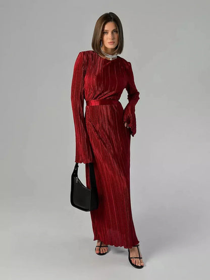 Model wearing the Velvet Flame Maxi Dress in marsala red, showcasing glossy pleats and flared sleeves.