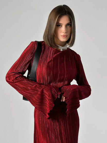 Model wearing the Velvet Flame Maxi Dress in glossy marsala with pleated design and flared sleeves.