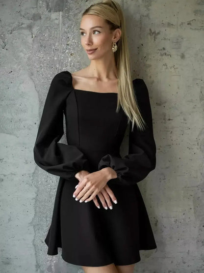 Model showcasing the Velvet Hour black mini dress with puffed sleeves and square neckline, perfect for weddings and special occasions.