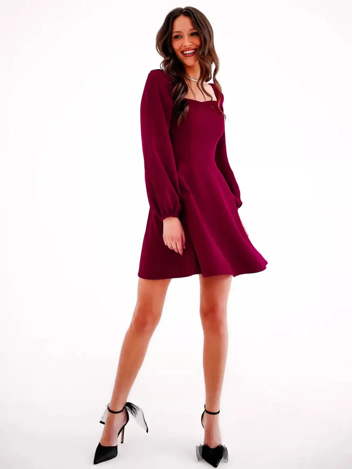 Stylish woman in a deep burgundy mini dress with long sleeves, perfect for formal events and wedding guest attire.