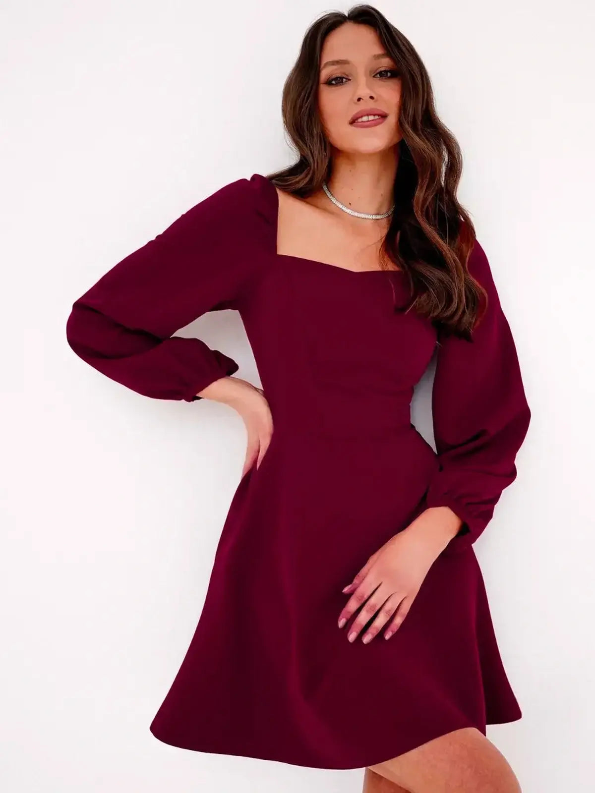 Model wearing a deep burgundy mini dress with a square neckline and voluminous long sleeves for elegant occasions.