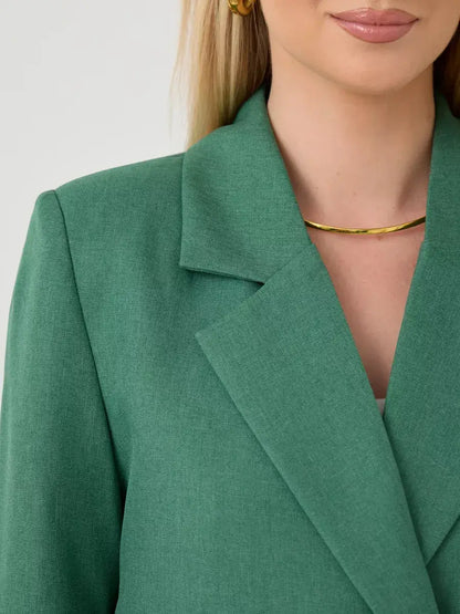 Close-up of a woman's Verde Blazer by Lauven, showcasing the oversized green tailored jacket collar and stylish accessories.