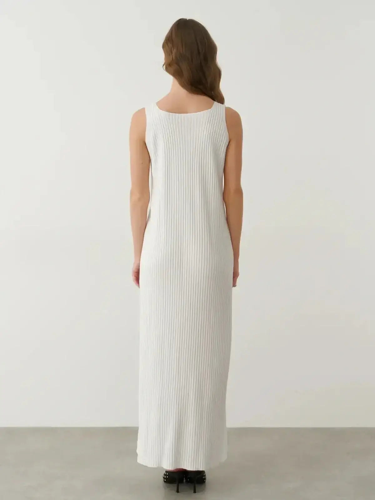 Back view of the Verona Maxi Dress in white ribbed cotton-acrylic knit, showcasing its elegant silhouette and side slit.