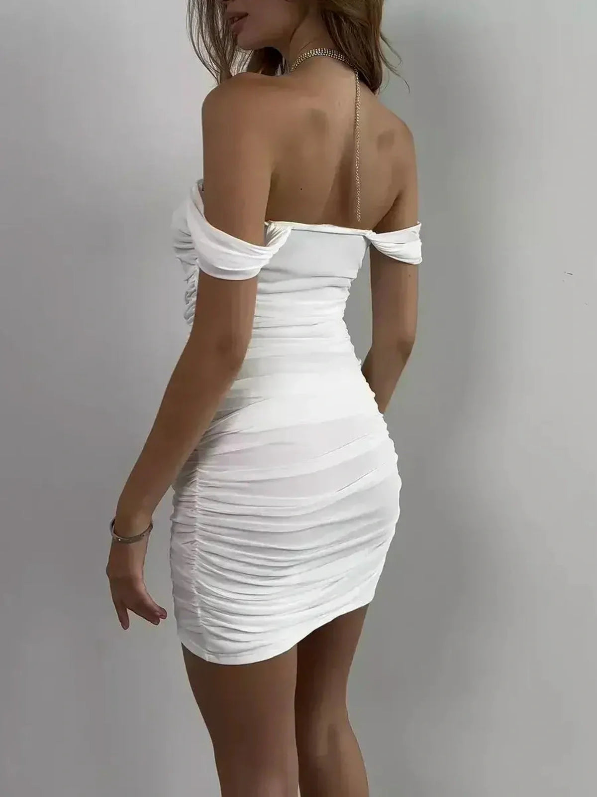 Model showcasing a white off-shoulder mini dress with ruching for a flattering silhouette, perfect for weddings and events.