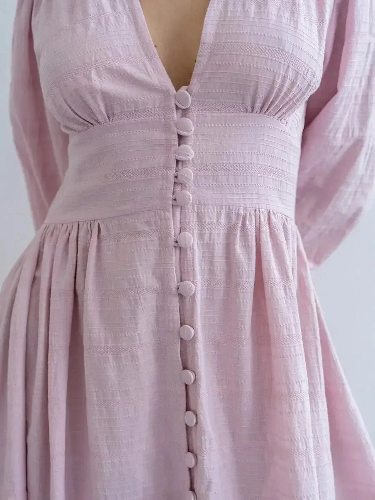 Close-up of the Willow Grace Maxi Dress in soft pink with a plunging V-neckline and textured button-front closure.