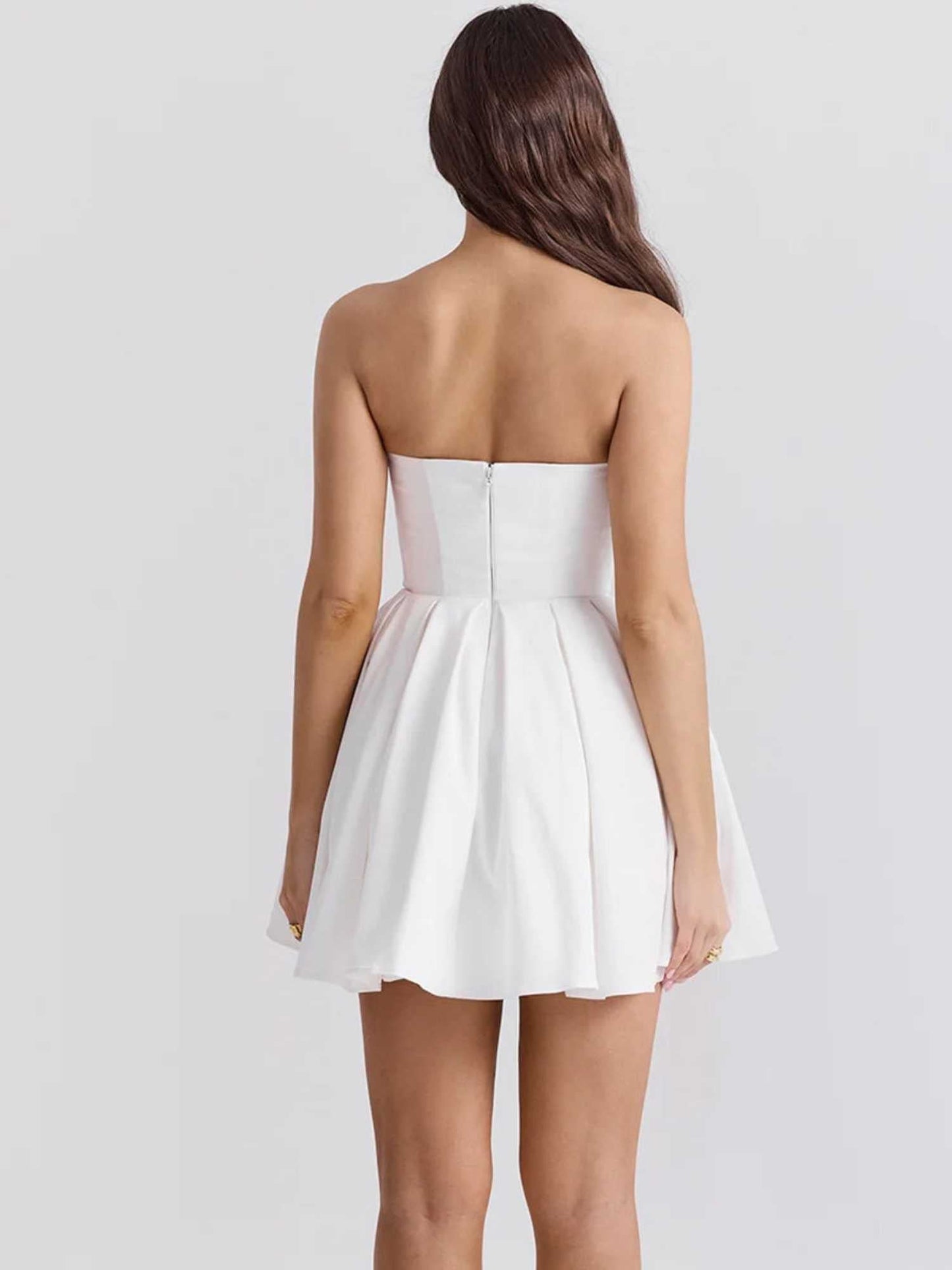 Back view of the Zara Mini Dress, a white strapless dress with a pleated skirt, perfect for summer and special occasions.