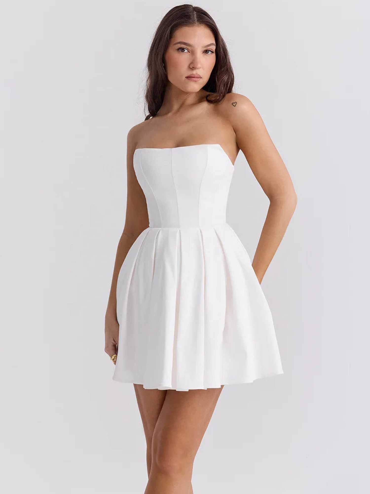 Elegant white mini dress with a sculpted bodice and pleated skirt, perfect for weddings and summer events.
